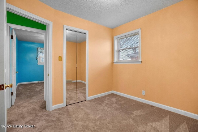 unfurnished bedroom with carpet, a textured ceiling, and a closet