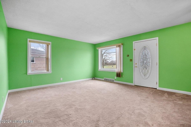 entrance foyer featuring light carpet and a textured ceiling