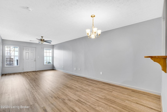 unfurnished living room with ceiling fan with notable chandelier, light hardwood / wood-style floors, and a textured ceiling