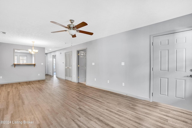 unfurnished living room with light wood-type flooring, a textured ceiling, and ceiling fan with notable chandelier