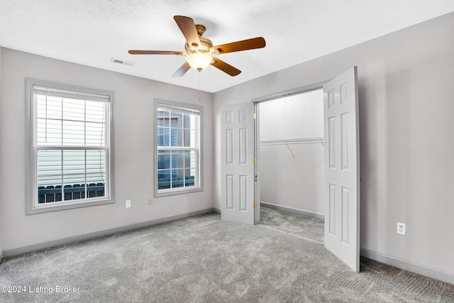 unfurnished bedroom with ceiling fan, a closet, light carpet, and a textured ceiling