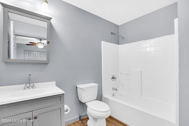 full bathroom featuring ceiling fan, hardwood / wood-style floors, toilet, vanity, and bathtub / shower combination