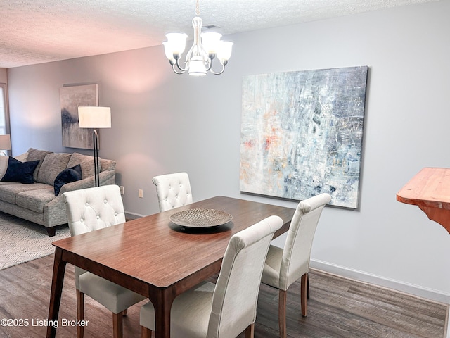 dining space featuring a textured ceiling, an inviting chandelier, and dark wood-type flooring