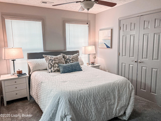 carpeted bedroom featuring ceiling fan, a closet, and a textured ceiling