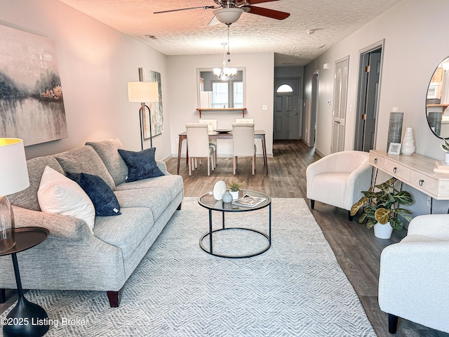 living room with ceiling fan with notable chandelier, wood-type flooring, and a textured ceiling