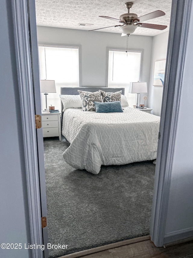 carpeted bedroom featuring ceiling fan and a textured ceiling