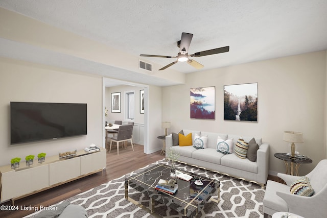 living room with a textured ceiling, ceiling fan, and dark hardwood / wood-style floors