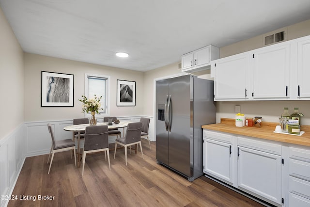 kitchen featuring stainless steel fridge, dark hardwood / wood-style flooring, and white cabinetry