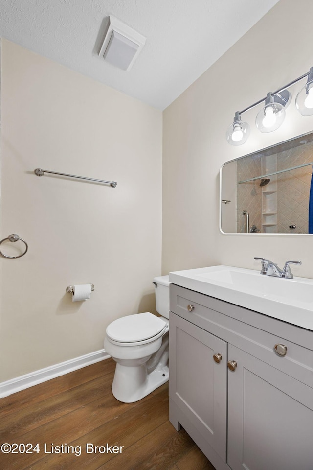 bathroom featuring a shower, hardwood / wood-style floors, vanity, and toilet