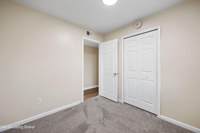 unfurnished bedroom featuring light colored carpet and a closet