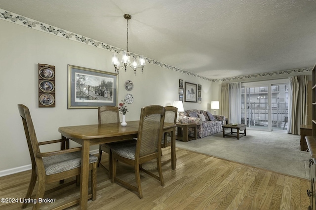 dining space with a textured ceiling, hardwood / wood-style flooring, and an inviting chandelier