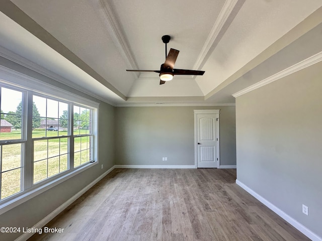 empty room featuring a raised ceiling, crown molding, hardwood / wood-style floors, and ceiling fan