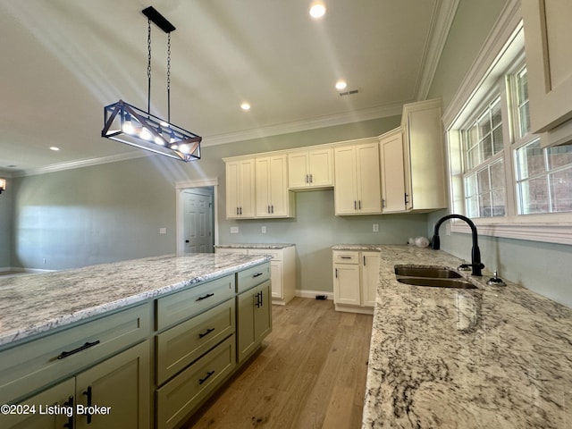 kitchen with light wood-type flooring, ornamental molding, sink, white cabinetry, and hanging light fixtures