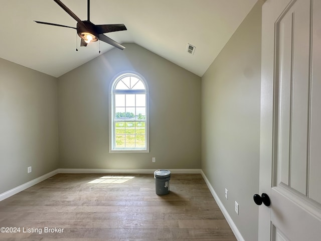 spare room with hardwood / wood-style floors, vaulted ceiling, and ceiling fan