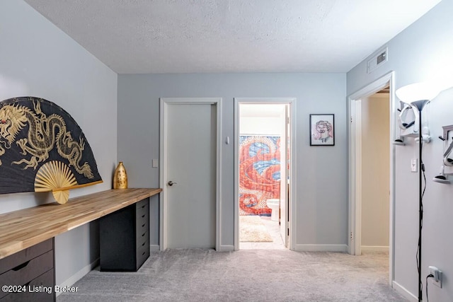 corridor featuring light carpet and a textured ceiling