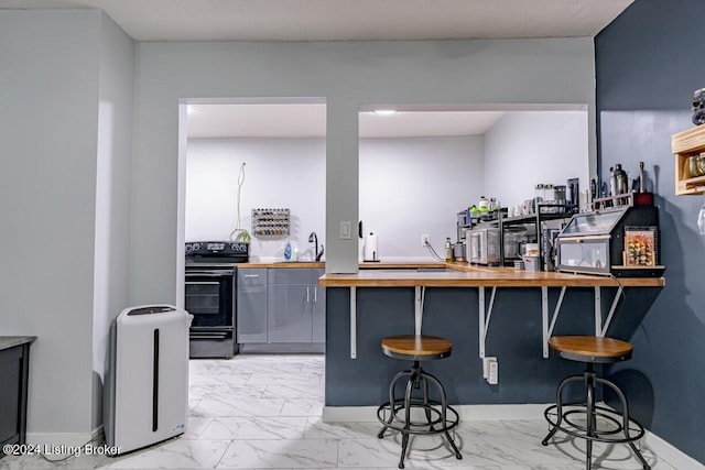 bar with electric range, gray cabinets, butcher block counters, and sink