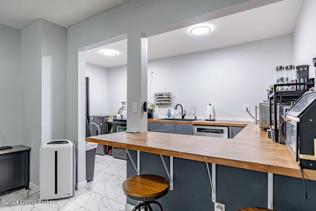 kitchen with kitchen peninsula, stainless steel dishwasher, butcher block counters, and sink