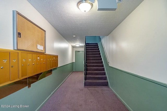 hallway featuring a mail area, carpet floors, and a textured ceiling