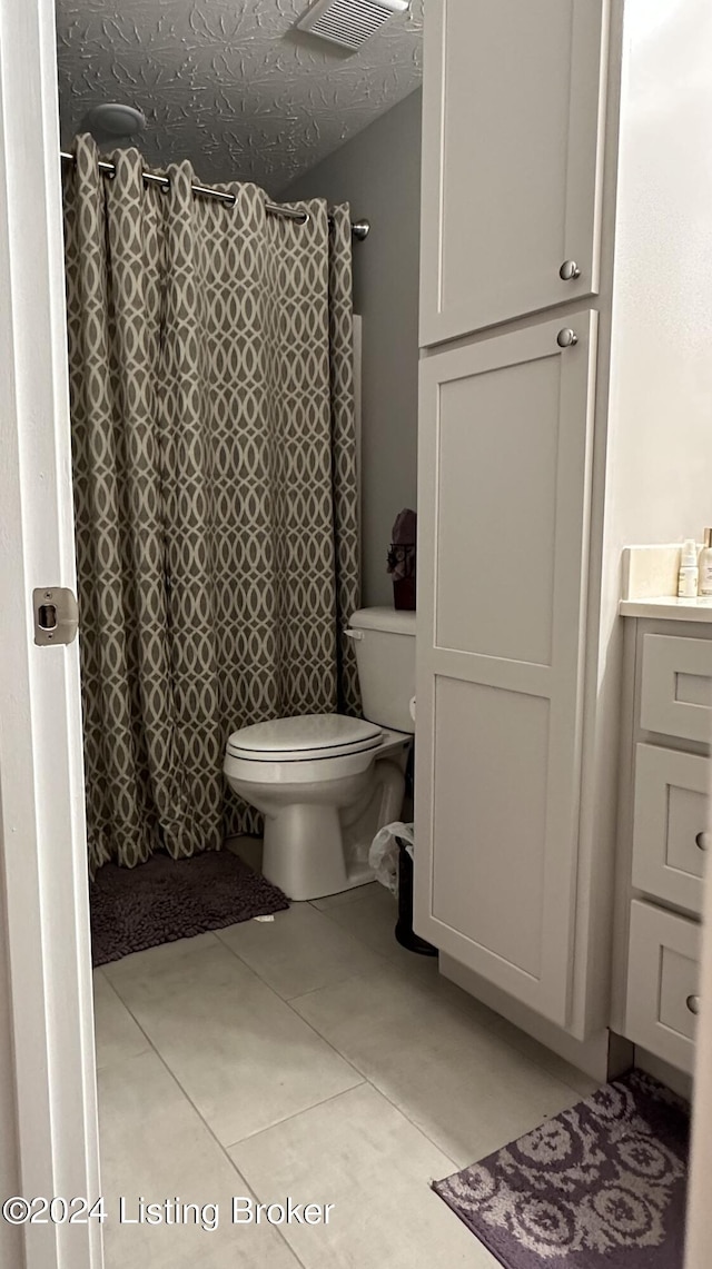 bathroom featuring toilet, vanity, tile patterned floors, and walk in shower