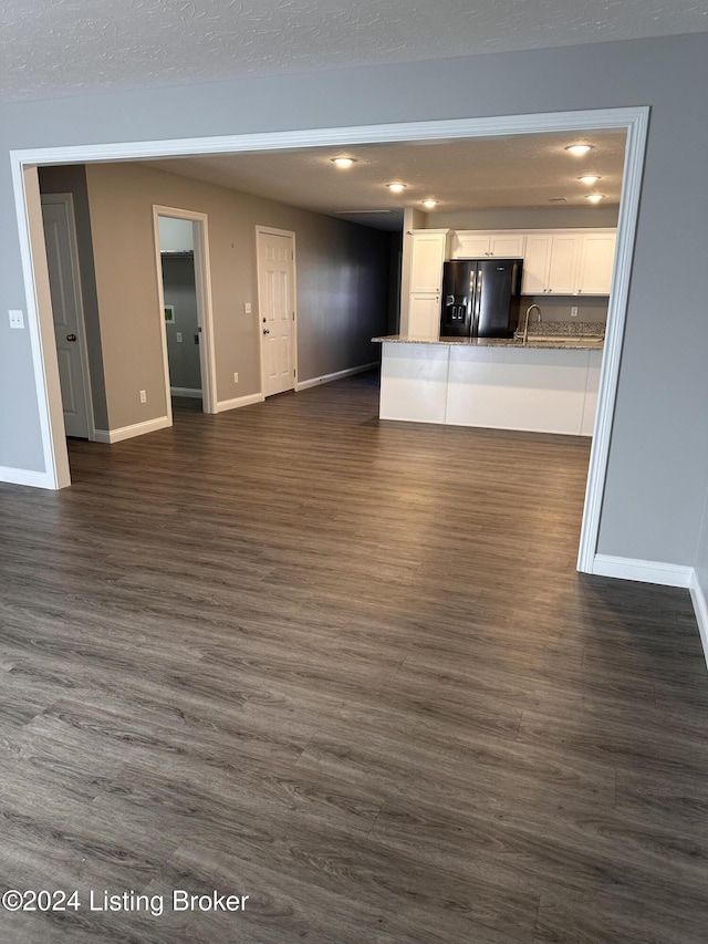 unfurnished living room with a textured ceiling, sink, and dark hardwood / wood-style floors