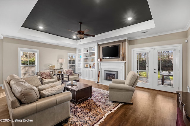 living room featuring french doors, a tray ceiling, ceiling fan, crown molding, and wood-type flooring