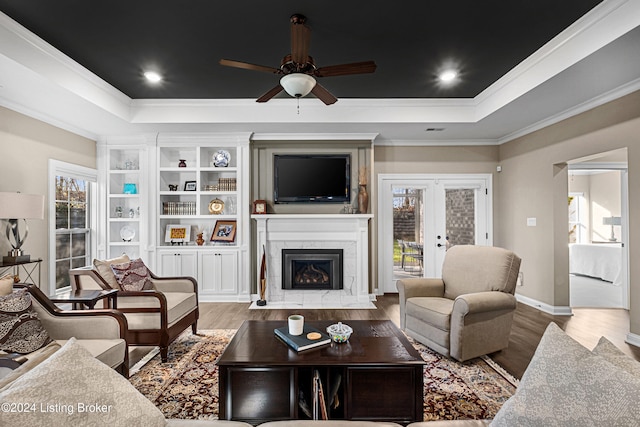 living room featuring hardwood / wood-style flooring, plenty of natural light, ornamental molding, and a tiled fireplace