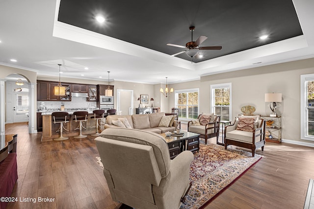 living room with crown molding, dark wood-type flooring, and a tray ceiling