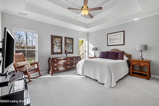 carpeted bedroom featuring ceiling fan, crown molding, and a tray ceiling