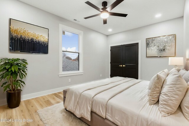 bedroom with ceiling fan, wood-type flooring, and a closet