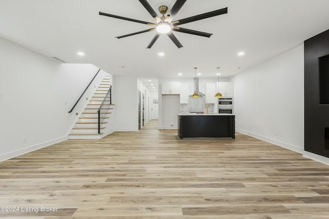 unfurnished living room featuring ceiling fan and light hardwood / wood-style flooring