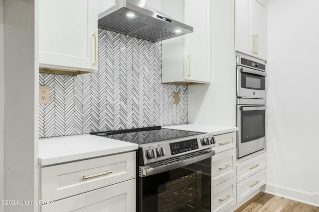 kitchen with white cabinetry, wall chimney range hood, and appliances with stainless steel finishes