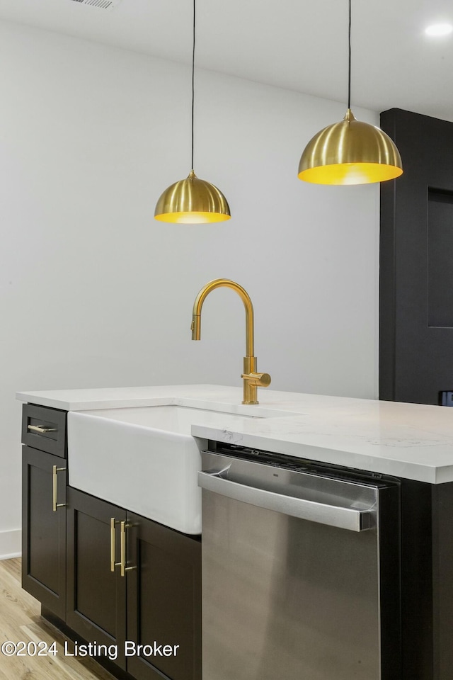 kitchen featuring stainless steel dishwasher, light hardwood / wood-style floors, light stone counters, and pendant lighting