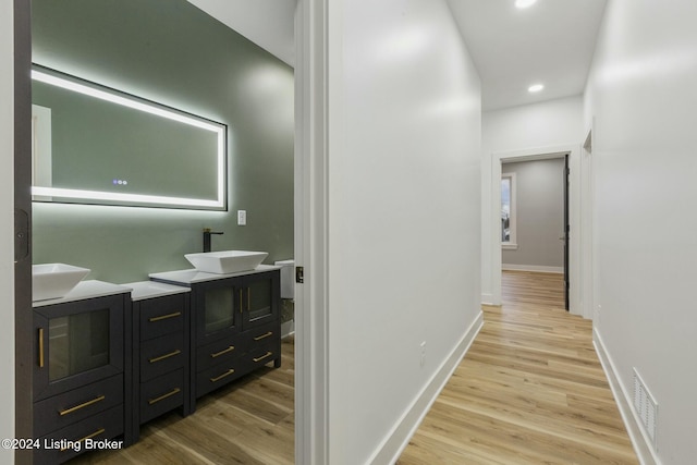 corridor with light wood-type flooring and sink