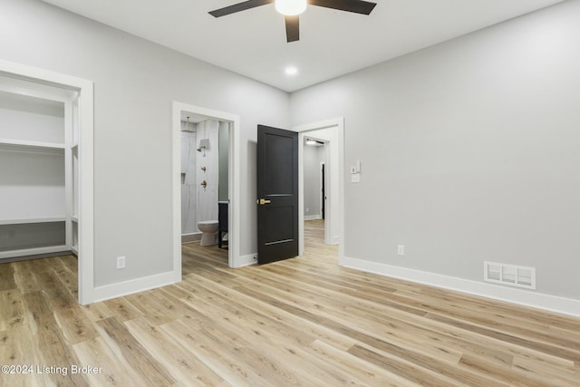 unfurnished bedroom featuring light hardwood / wood-style floors, a spacious closet, a closet, and ensuite bath