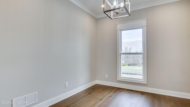 empty room with hardwood / wood-style floors, ornamental molding, and a chandelier