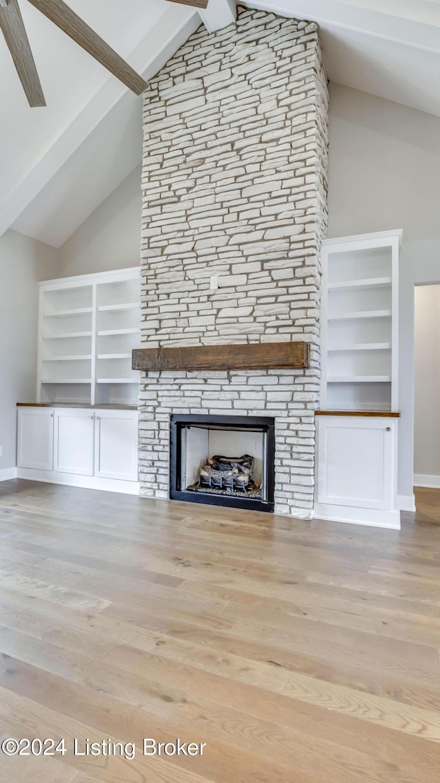 unfurnished living room featuring vaulted ceiling with beams, a stone fireplace, and light hardwood / wood-style flooring