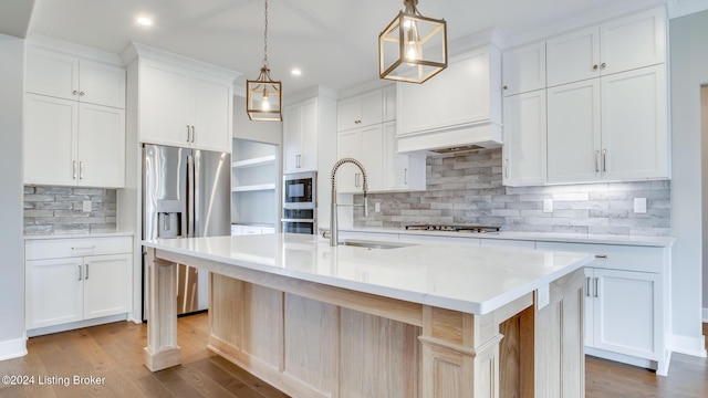 kitchen with white cabinets, pendant lighting, a center island with sink, and sink