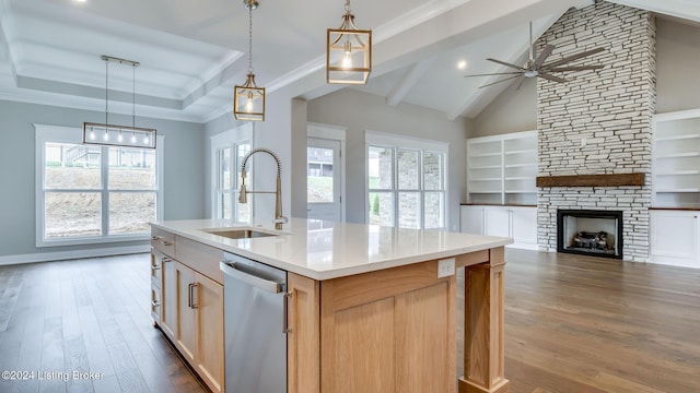 kitchen with stainless steel dishwasher, a kitchen island with sink, sink, light brown cabinets, and dark hardwood / wood-style floors