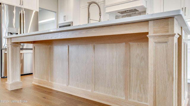 kitchen with stainless steel fridge with ice dispenser, sink, and light wood-type flooring