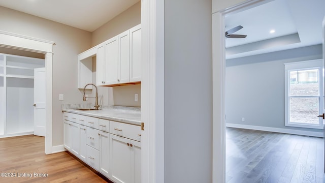 kitchen with white cabinets, ceiling fan, sink, and light hardwood / wood-style flooring