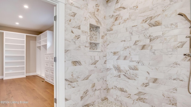 bathroom featuring a tile shower and wood-type flooring