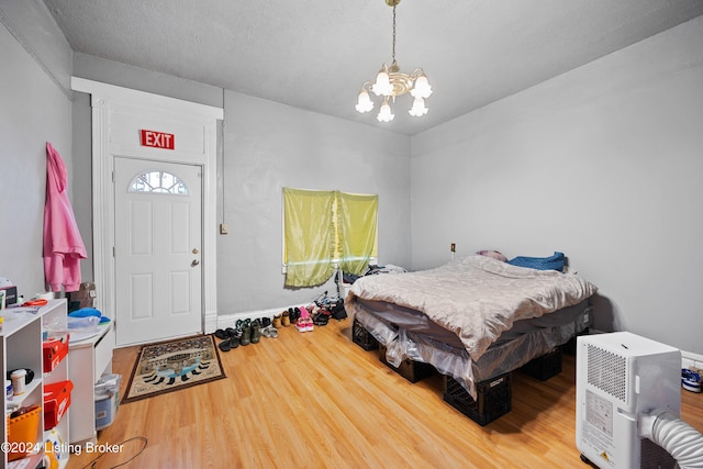 bedroom featuring wood-type flooring, a textured ceiling, and a notable chandelier