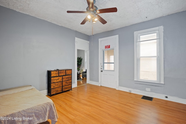 bedroom featuring ceiling fan, hardwood / wood-style floors, and a textured ceiling