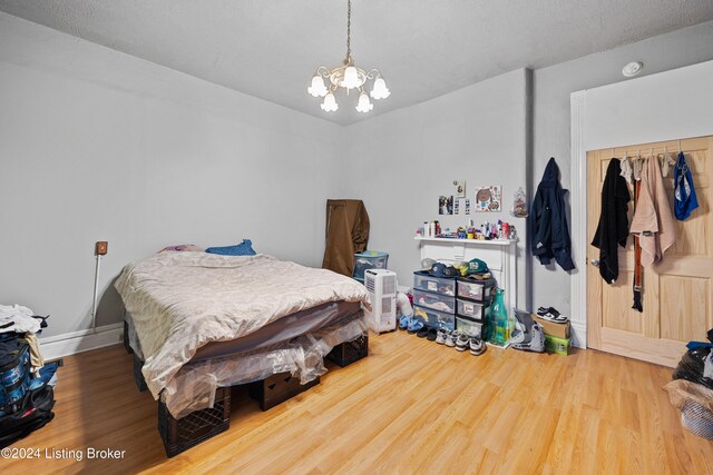 bedroom with wood-type flooring, a closet, and a notable chandelier