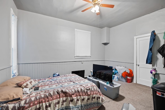 bedroom featuring carpet floors, ceiling fan, and wood walls