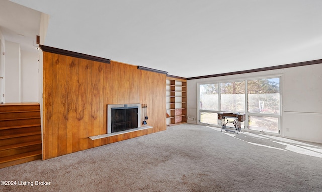 unfurnished living room with carpet flooring, built in shelves, and ornamental molding