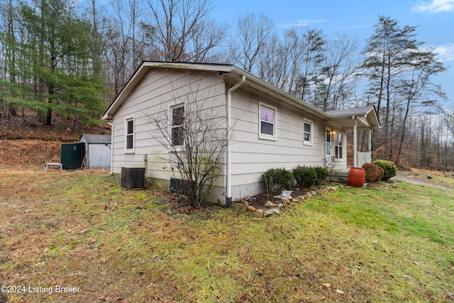 view of property exterior featuring a lawn, central AC unit, and a shed