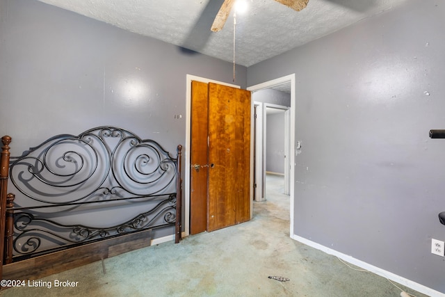 unfurnished bedroom with ceiling fan, light colored carpet, and a textured ceiling