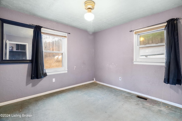 carpeted empty room featuring a textured ceiling