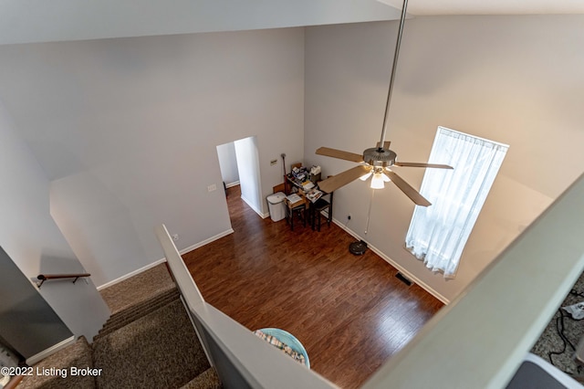 stairs featuring high vaulted ceiling, ceiling fan, and hardwood / wood-style flooring